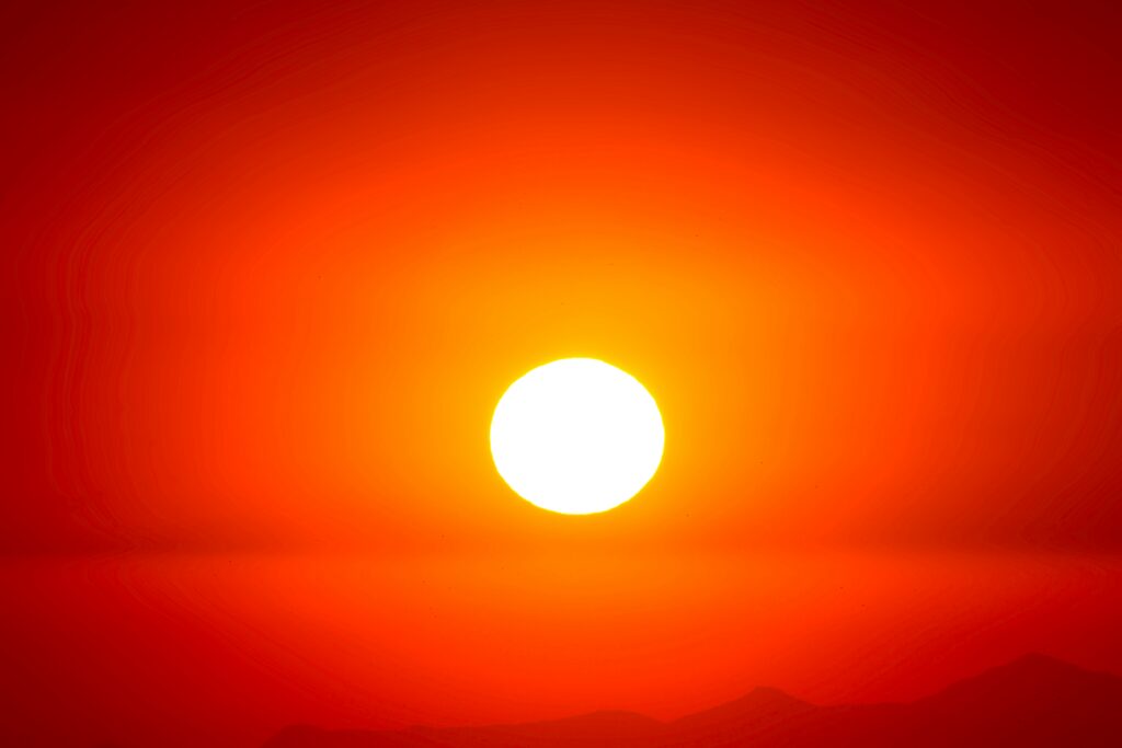 Soleil éclatant dans un ciel rouge et orange illustrant un épisode de fortes chaleurs ou de canicule.